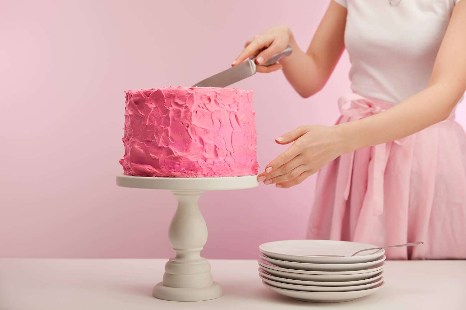 baking-tools-4 a person cutting a pink cake