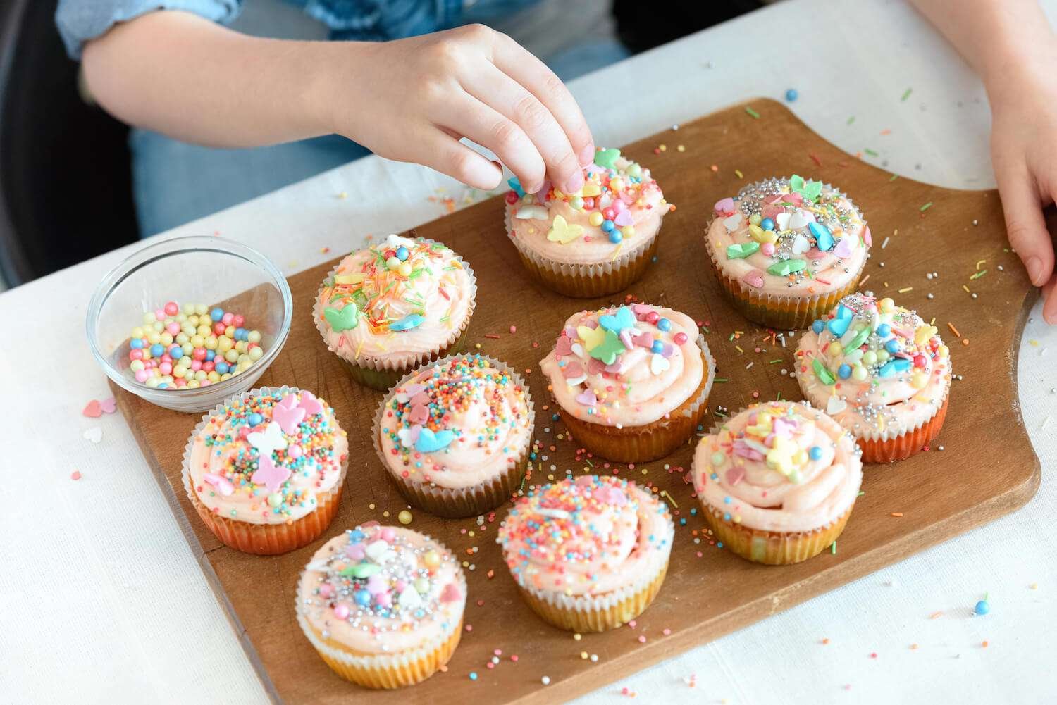 a person decorating cupcakes with sprinkles