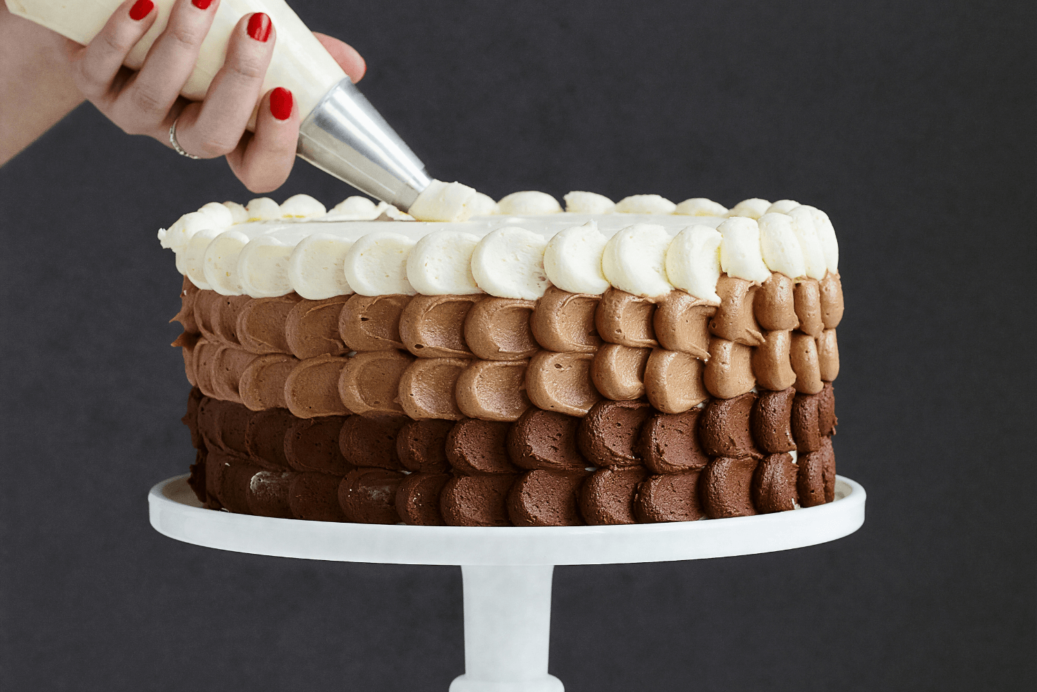 a hand holding a piping bag over a cake